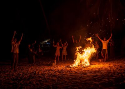 Group of travelers enjoying a beach bonfire on Isla Franklin, San Blas — a cozy evening tradition under the stars.