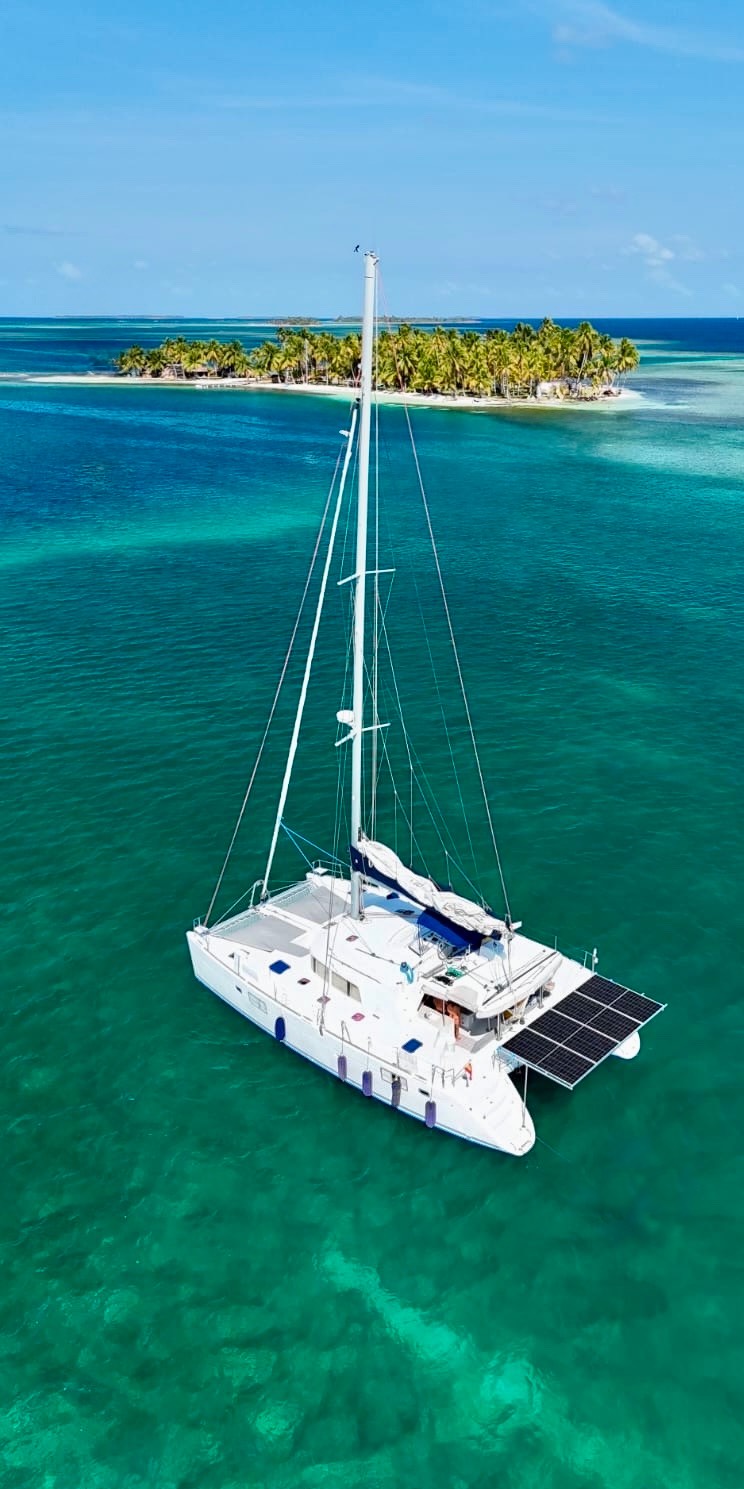 Catamarán anclado en aguas turquesas cerca de una isla tropical en San Blas, Panamá