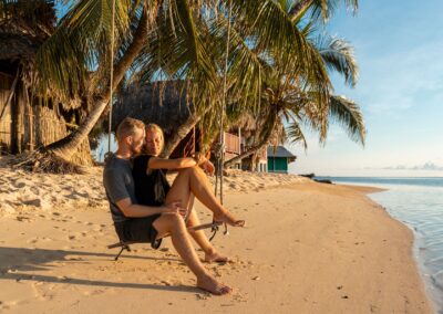 Romantic couple on a beach swing at sunset on Isla Franklin, San Blas — a perfect moment in paradise.