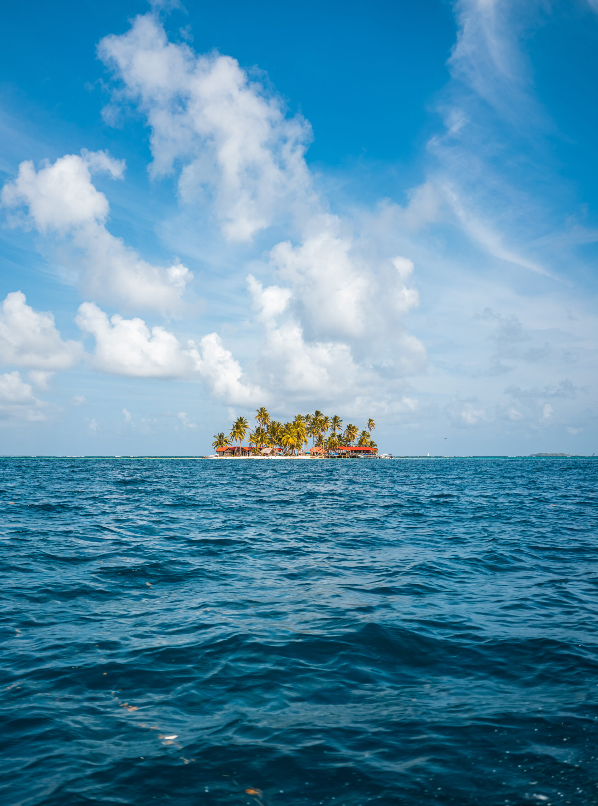 san-blas-guna-yala-island-from-boat Isla remota de San Blas (Guna Yala) con palmeras, vista desde un bote en el mar Caribe.